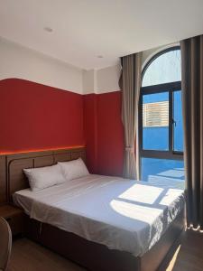 a bedroom with a bed with a red wall and a window at Airport Homestay 2 in Danang