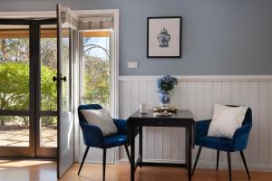 a dining room with a table and two blue chairs at Oscars in Hepburn Springs