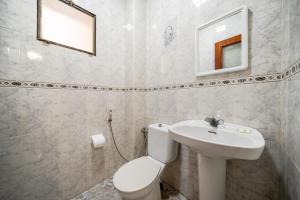 a white bathroom with a toilet and a sink at Spacious Apartment 1 min from Beach in Tangier