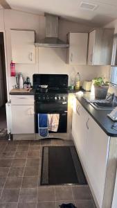 a kitchen with a black stove and white cabinets at Beach getaway in King's Lynn