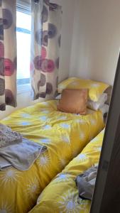 a bed with yellow sheets and pillows in a room at Beach getaway in King's Lynn +2 photos
