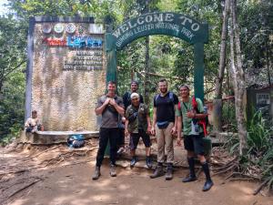 a group of men standing in front of a sign at Orangutan Inn in Bukit Lawang