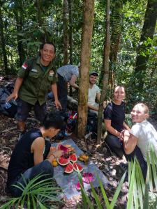 a group of people sitting around a table in the forest at Orangutan Inn in Bukit Lawang +11 photos