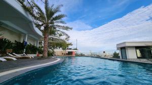 a swimming pool with a palm tree next to a building at Babylon Mini Resort in Vung Tau
