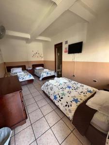 a room with three beds and a flat screen tv at Hotel la Ermita in Las Victorias
