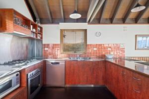 a kitchen with wooden cabinets and a stove top oven at Cobungra Chalet in Mount Hotham