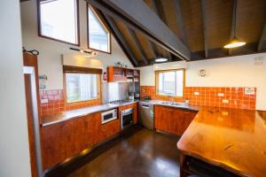 a large kitchen with wooden cabinets and a wooden table at Cobungra Chalet in Mount Hotham +2 photos