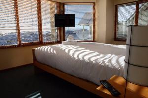 a bedroom with a bed and a tv and windows at Cobungra Chalet in Mount Hotham