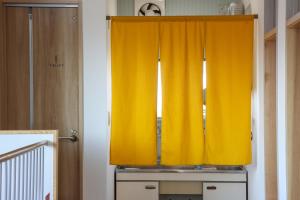 a yellow curtain on a window in a room at たっこ宿 in Takko