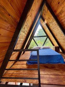 a bed in a wooden room with a window at Glamping Encanto Amazónico Macas in General Proaño