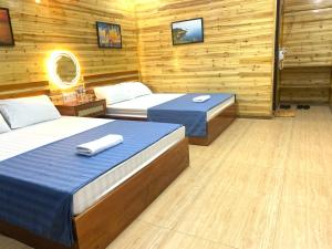 two beds in a room with wooden walls at Huy Hùng Cô Tô in Nam Cap