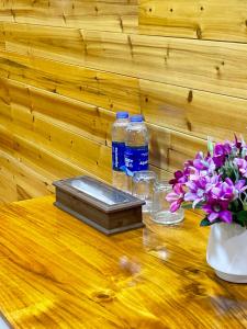 two bottles of water and flowers on a wooden table at Huy Hùng Cô Tô in Nam Cap