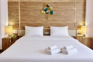 ein Schlafzimmer mit einem weißen Bett, auf dem Handtücher liegen in der Unterkunft Asian Hotel in Hat Yai