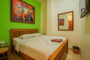 a bedroom with a bed with a green wall at The Cabin Hotel Mantrijeron in Yogyakarta