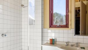 a white tiled bathroom with a sink and a window at Gundanora Chalet in Mount Hotham +18 photos