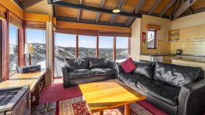 a living room with a leather couch and a table at Gundanora Chalet in Mount Hotham