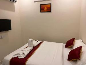 a bedroom with a bed with white sheets and red pillows at Du Auro Residency in Kuilapayam +4 photos