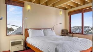 a bed in a room with two large windows at Gundanora Chalet in Mount Hotham