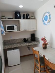 a small kitchen with a table and a microwave at Inefável flat Porto Marina Resort in Mangaratiba