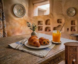 a table with a plate of croissants and a glass of orange juice at Spacious Apartment 1 min from Beach in Tangier