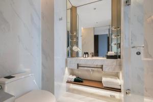 a bathroom with a toilet and a sink and a mirror at Grand Madison Hotel Hangzhou in Hangzhou