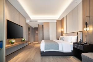 a hotel room with a bed and a flat screen tv at Grand Madison Hotel Hangzhou in Hangzhou +16 photos