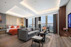 a hotel room with a bed and a couch and a tv at Grand Madison Hotel Hangzhou in Hangzhou