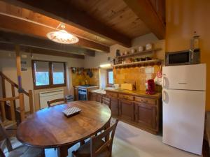 a kitchen with a wooden table and a white refrigerator at La cabane de Thuriès in Camarès