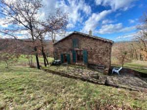 an old stone house with a bench in a field at La cabane de Thuriès in Camarès