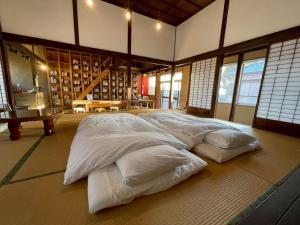 a large white bed in a room with windows at 泊れる図書館 さんごさん in Goto