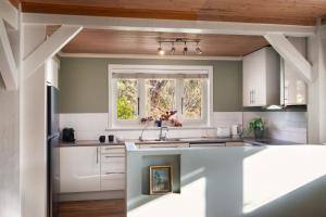 a kitchen with white cabinets and a window at El Camino in Hepburn Springs