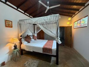 a bedroom with a canopy bed with a ceiling fan at Angelica Villa in Bentota