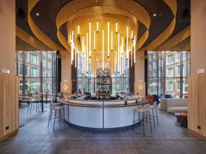 a bar in a hotel lobby with a chandelier at TRIBE Milano Malpensa in Vizzola Ticino