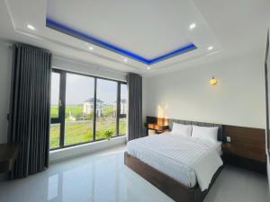 a bedroom with a bed and a large window at Hotel Trâm Anh 3 in Nhơn Trạch