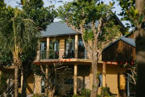 a large house with a balcony and trees at May Farm in Hương Hóa