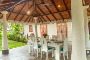 a white table and chairs under a wooden roof at Angelica Villa in Bentota
