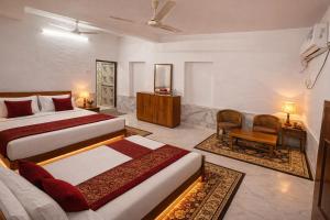 a hotel room with two beds and a chair at Tripathi's Rampath Inn Ayodhya in Ayodhya