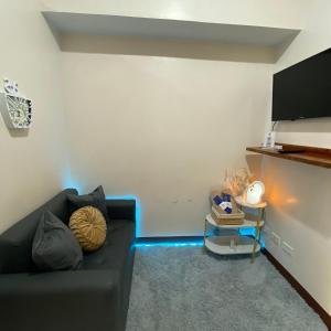 a living room with a black couch and a tv at MGs Dwell - Baguio Transient at Moldex Residences in Baguio