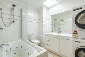 a white bathroom with a tub and a toilet and a sink at Apartment 9T in Lennox Head +1 photo