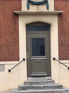 a green door on a building with stairs at Le Cocon des Remparts in Gravelines