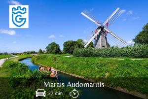 a windmill in the middle of a river with people on a boat at Le Cocon des Remparts in Gravelines
