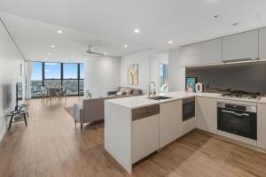 a kitchen with white cabinets and a living room at 2B2B High Floor Apt with RiverView & Parking in Brisbane