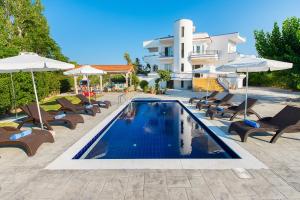 a swimming pool with chairs and umbrellas next to a house at Villa Giovanni in Faliraki