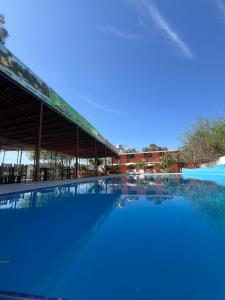 a large swimming pool with a building in the background at Hospedaje Los Pecanos in Ica +14 photos
