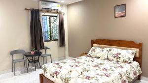 a bedroom with a bed and a table and a window at Collection O Southern Star Resort Pattaya in North Pattaya