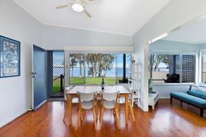 a kitchen and living room with a table and chairs at Lakes Edge Cottage Pet Friendly Waterfront Escape in Budgewoi