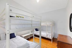 a bedroom with two bunk beds and a desk at Lakes Edge Cottage Pet Friendly Waterfront Escape in Budgewoi