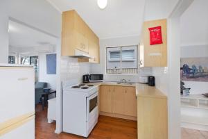 a kitchen with a white stove and a sink at Lakes Edge Cottage Pet Friendly Waterfront Escape in Budgewoi +8 photos