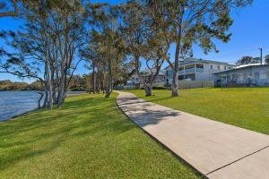 a walkway through a park next to a body of water at Lakes Edge Cottage Pet Friendly Waterfront Escape in Budgewoi