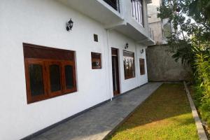 a white building with wooden doors and a yard at Long Villa in Kandy